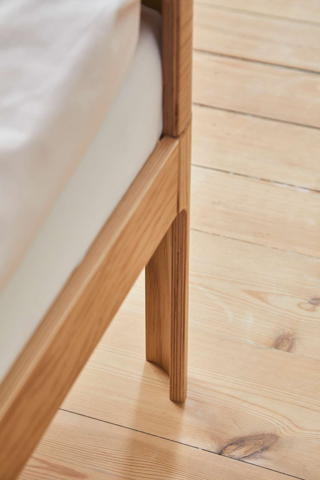 Lit FLEXA BABY, finition chêne, 140 x 70 cm, avec matelas posé sur un parquet clair ; bords arrondis pour la sécurité de lenfant.