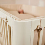 FLEXA-Babybett, 140 x 70 cm, cremefarben, sichtbare weiche Polsterung, Kind liegt darin; im Kinderzimmer.