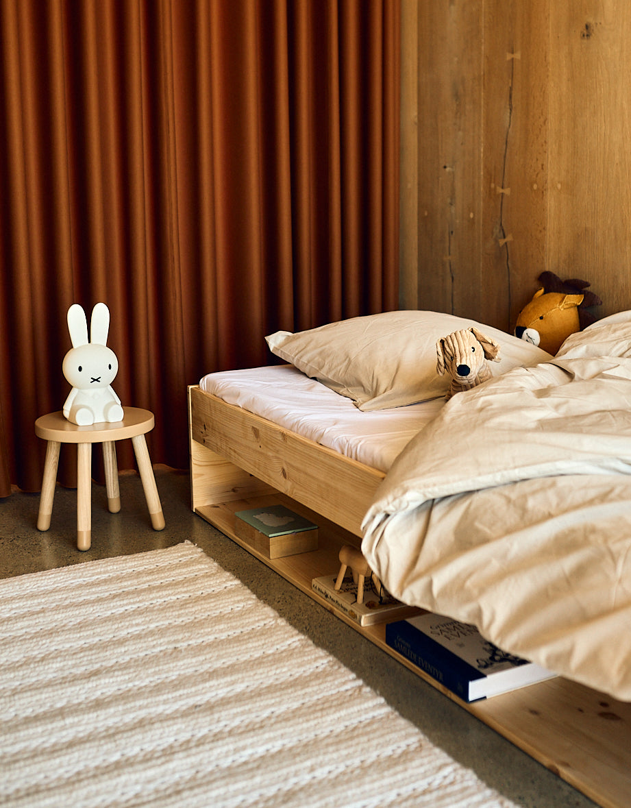 FLEXA DOTS Kinderhocker in zartem Rosa, kindersicheres Design, in einem Kinderzimmer mit Holzbett und orangefarbenem Vorhang.